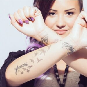 Demi Lovato: birds flying out of the word “Faith”.